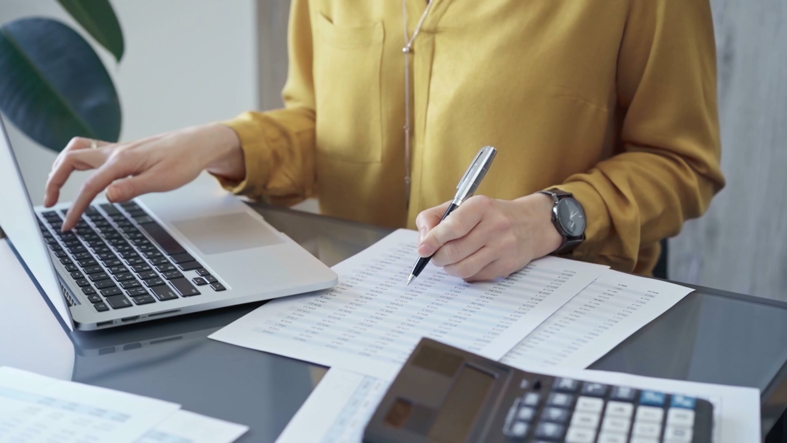 Professional business woman in yellow blouse is working on financial reports. Close-up of a woman's hands as she works on finance documents. Audit and taxes.